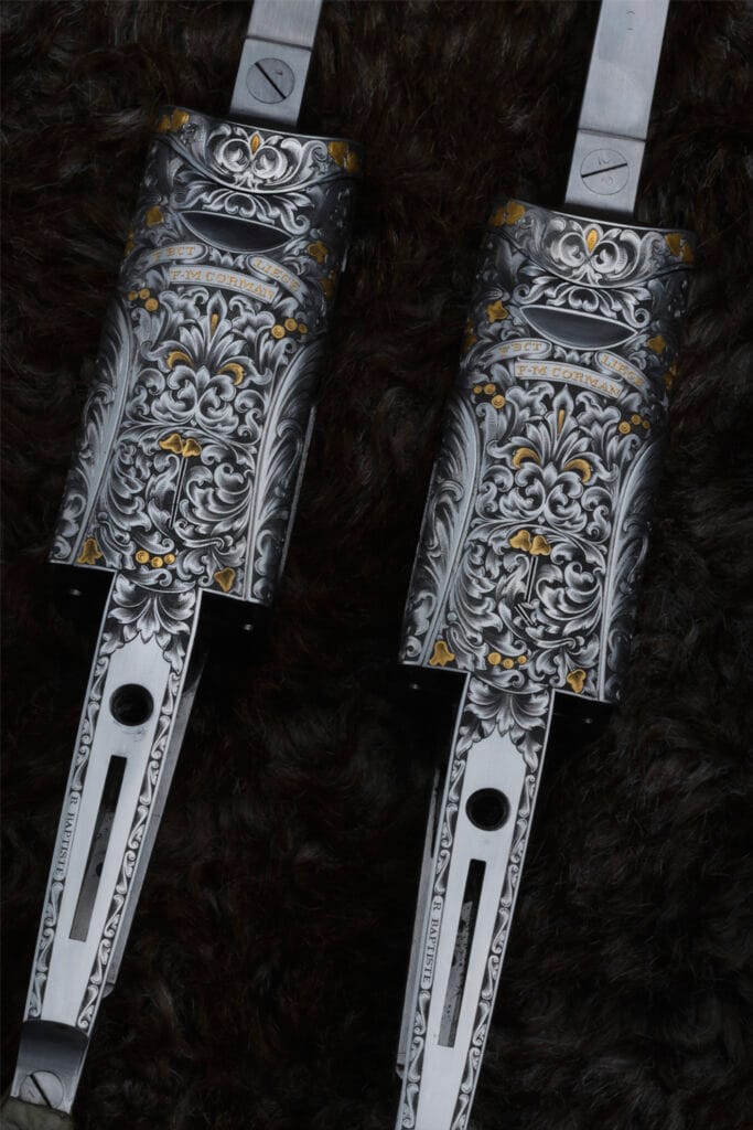Détail de deux bascules de fusil de chasse de prestige gravées main de motifs d'acanthe denses avec incrustations d'or 24K par RBaptiste.